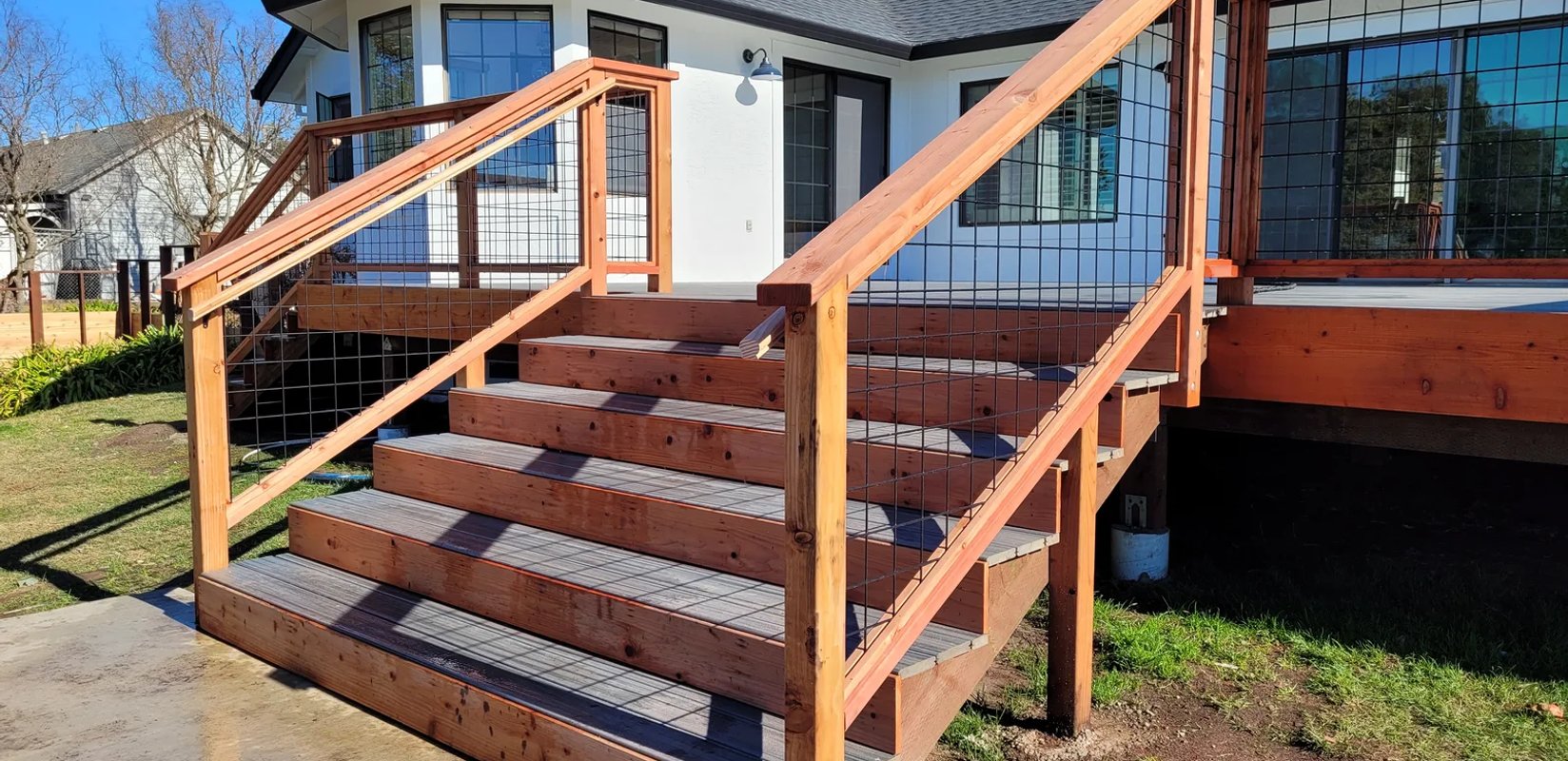 Exterior deck staircase with wood handrails and wire infill panels