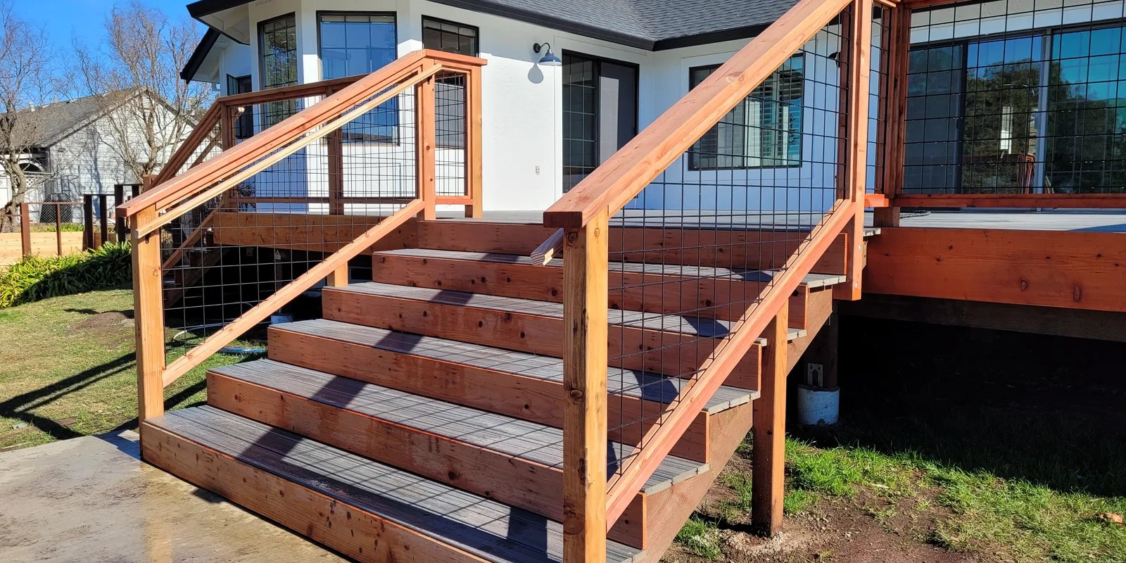 Exterior deck staircase with wood handrails and wire infill panels