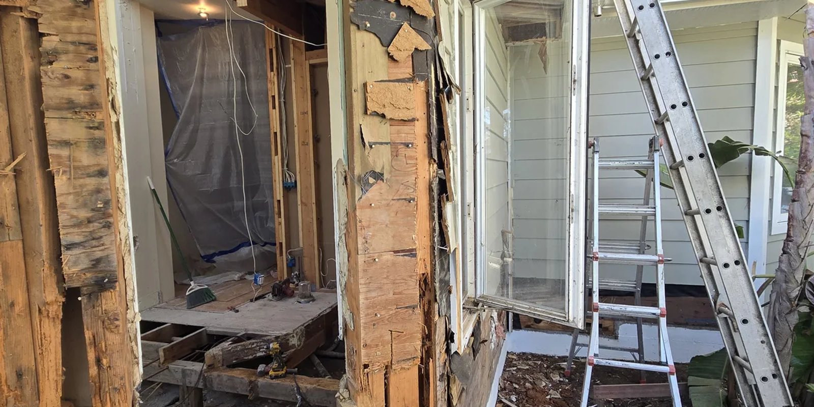 Exterior siding removed to expose framing beside a doorway