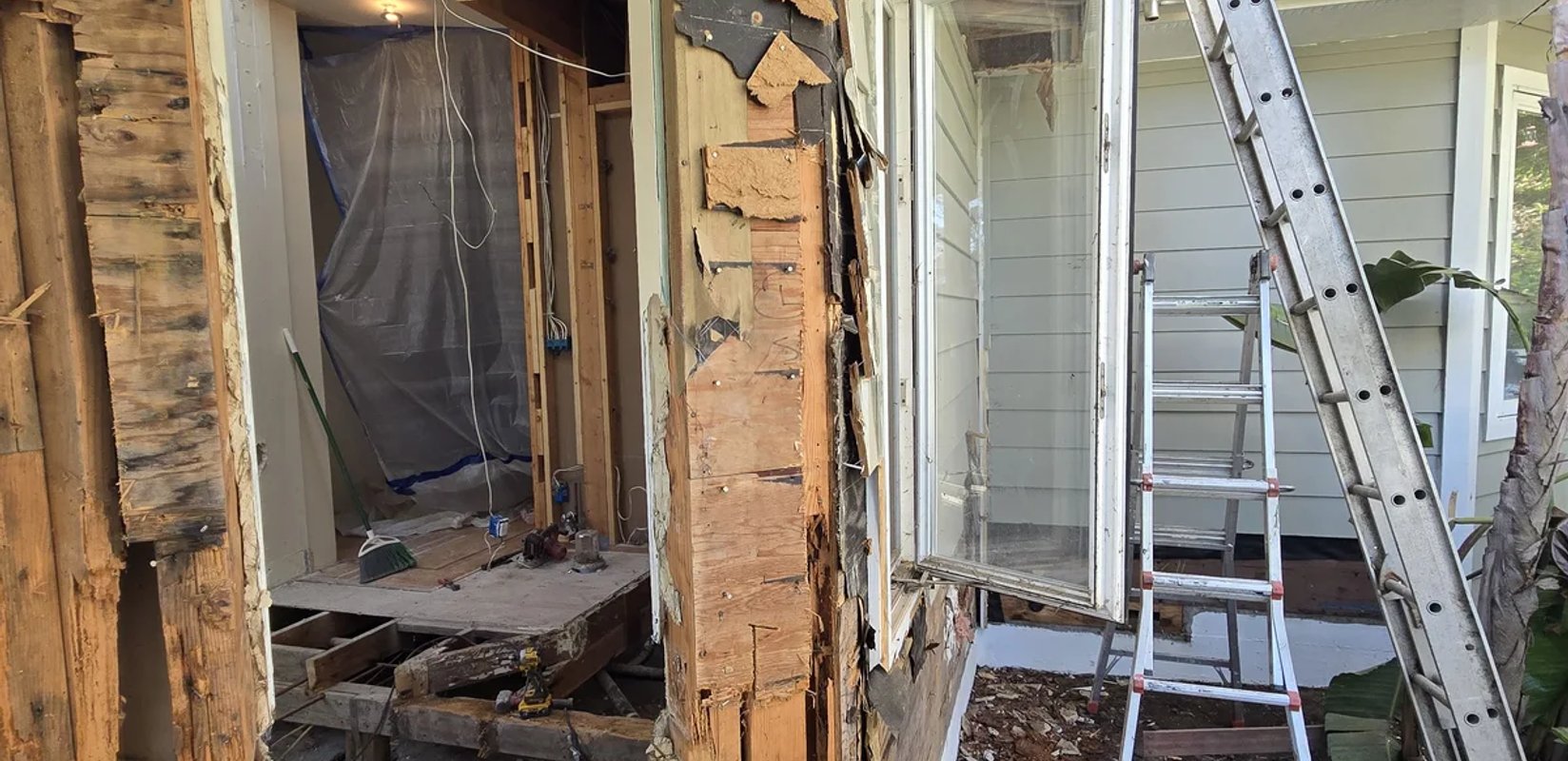 Exterior siding removed to expose framing beside a doorway