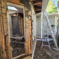Exterior wall opened beside a doorway for wood repairs