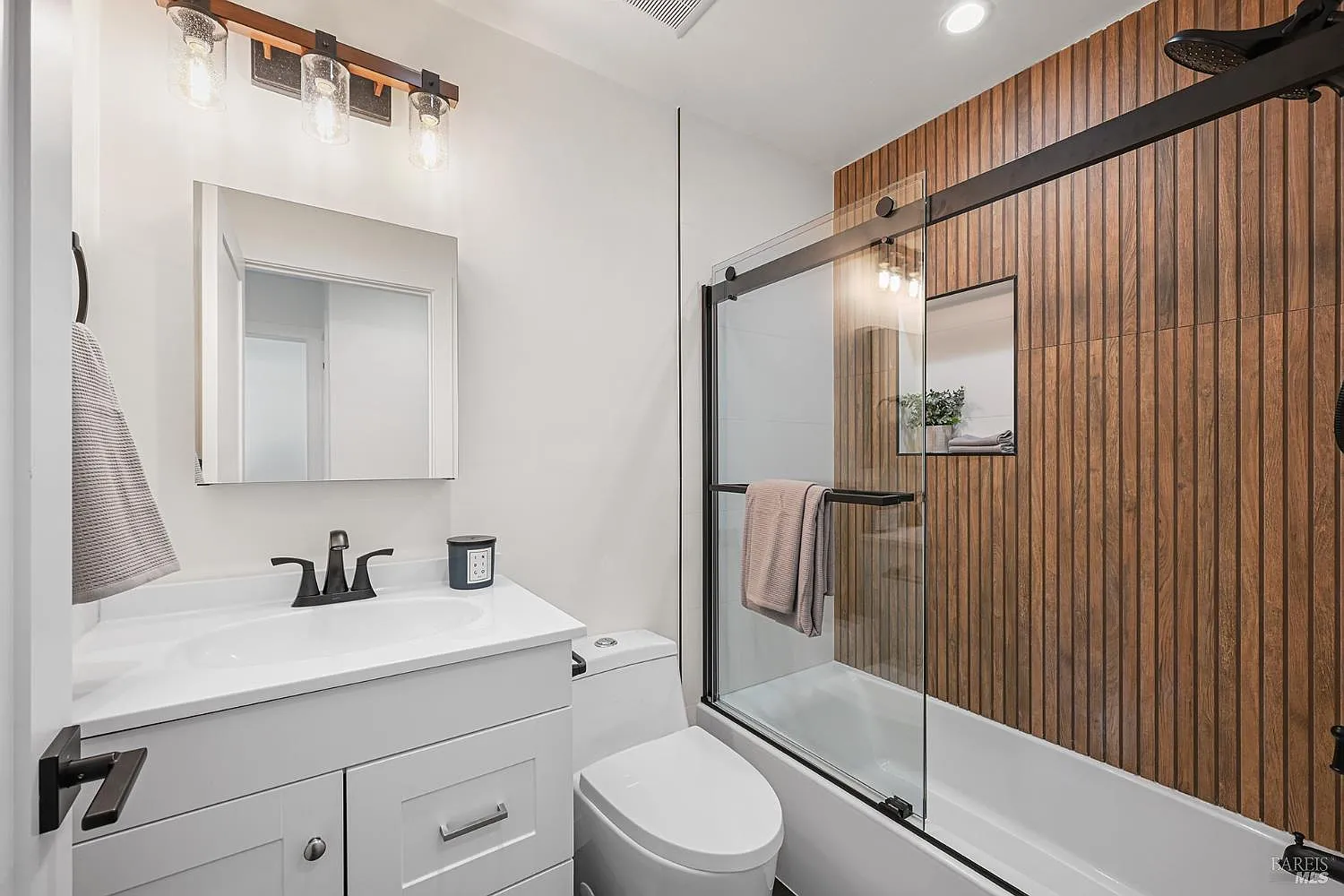 bathroom remodel with white vanity and wood accent wall
